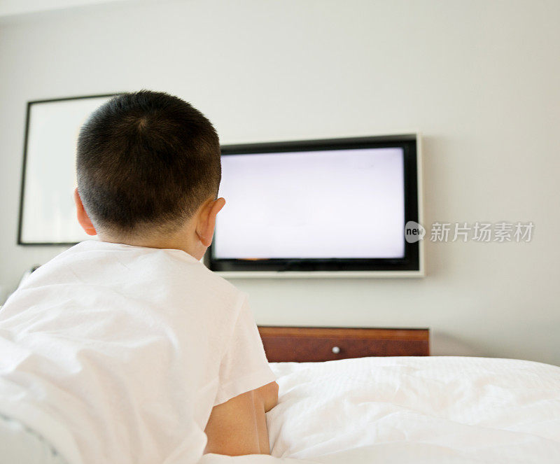 小男孩在床上看电视