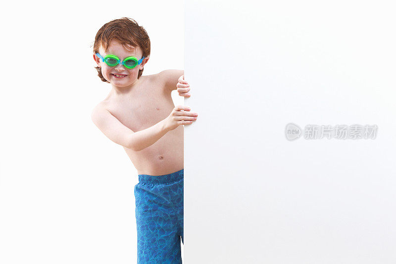 男孩在游泳短裤环顾四周白墙在工作室