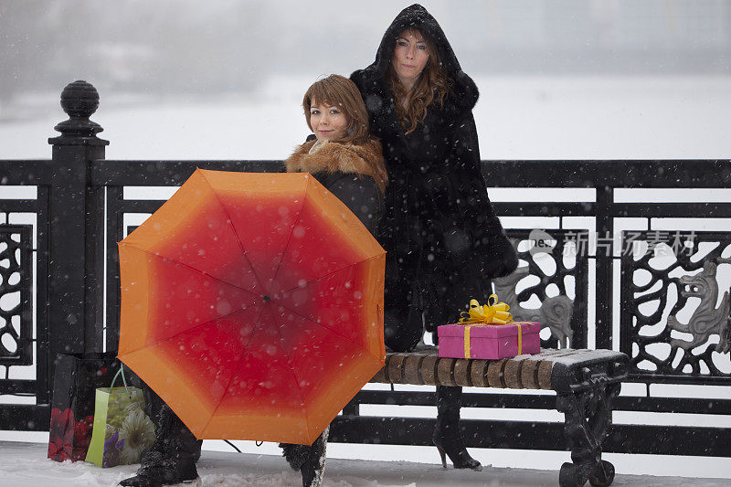 女孩们:在下雪的时候带着橙色的伞和礼物