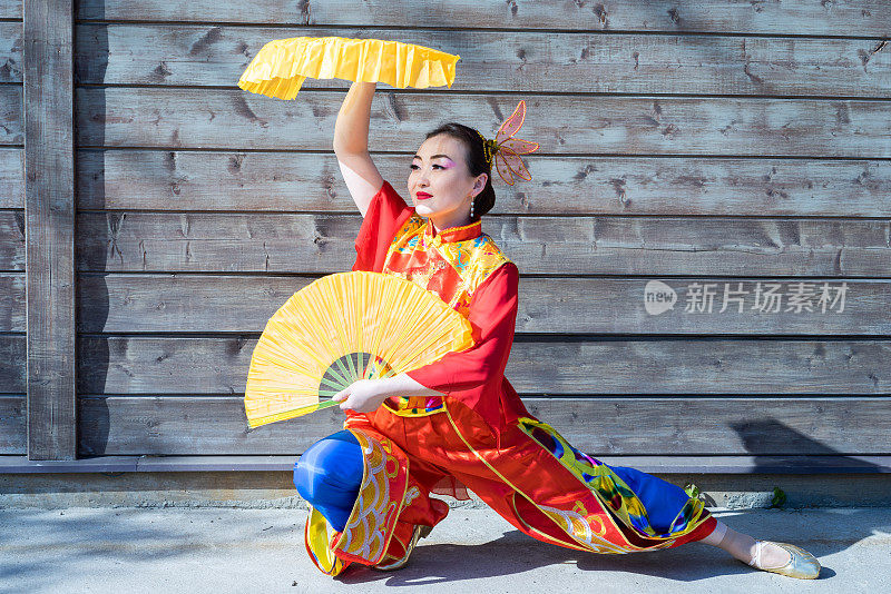 穿着中国传统服装的漂亮女人，拿着两把大黄色扇子