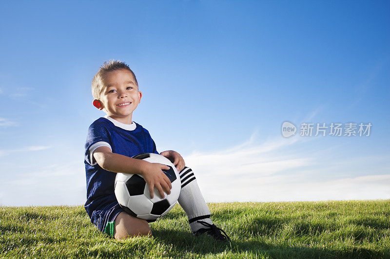 一个穿着足球制服的小男孩在球场上的肖像