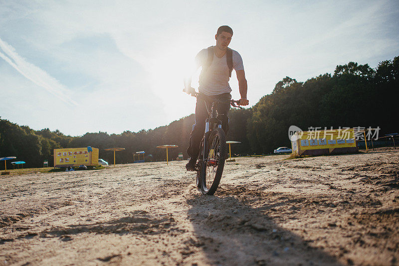 日落时分，骑自行车的人沿着海滩骑行