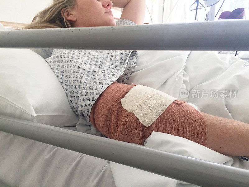 一位妇女躺在医院的病床上，手臂上缠着绷带