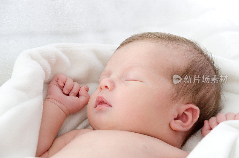 睡在白色毯子里的女婴。