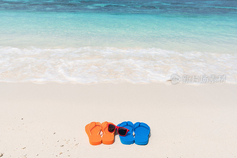 热带海滩上的太阳镜和彩色凉鞋