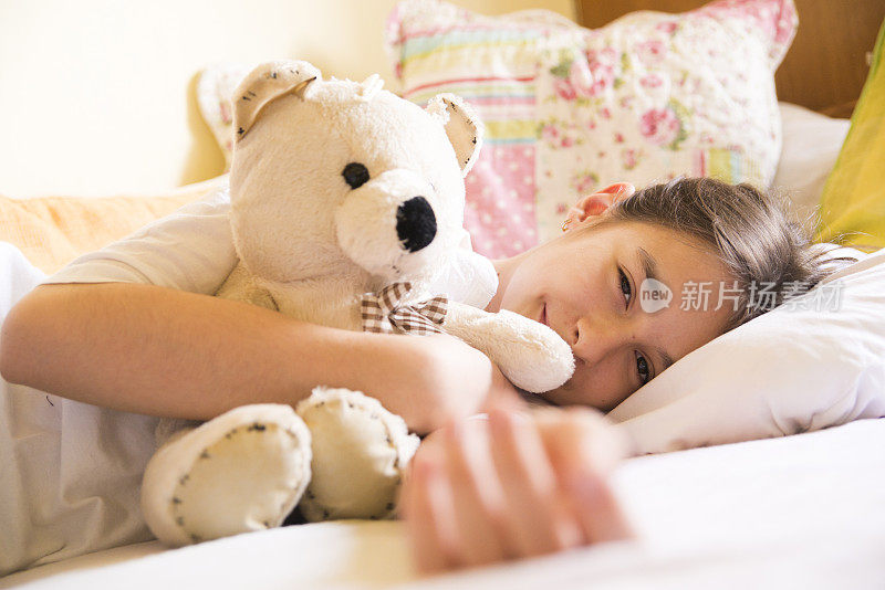 女孩和泰迪熊躺在床上