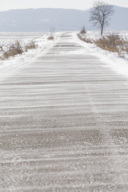 大风把雪吹在柏油路上