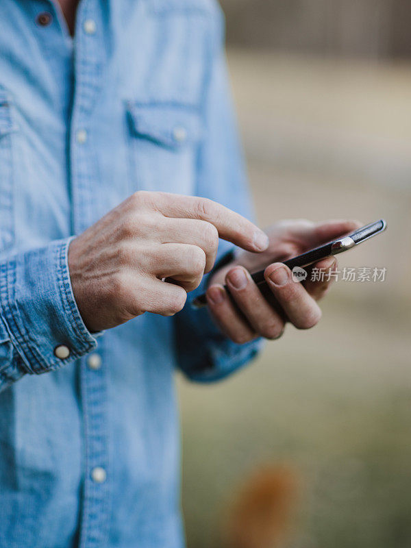 英俊的真正的男人在户外与智能手机