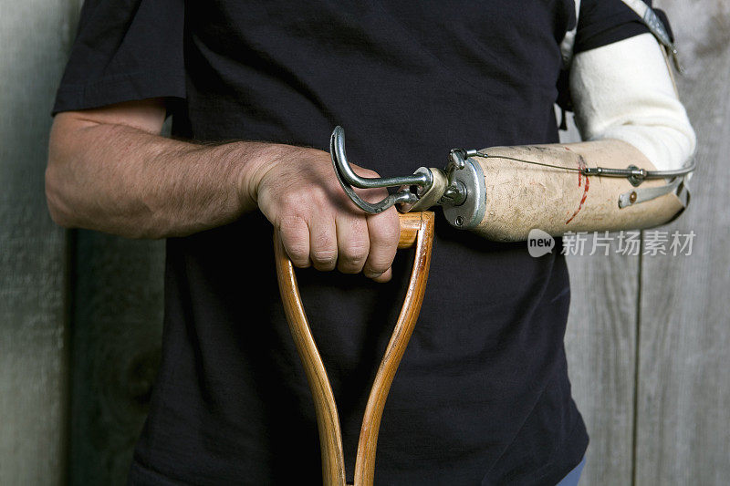 人的手和假肢握着铲子的把手。