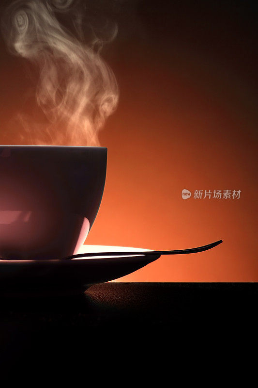 橙色背景的热咖啡杯和勺子