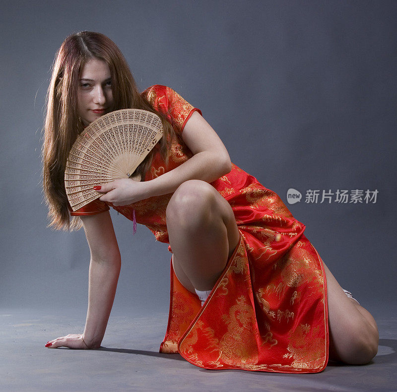年轻漂亮的长发女孩穿着中国红色和服，带着扇子