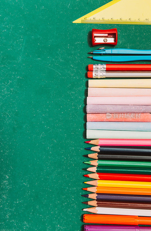 学校物品，铅笔，蜡笔和粉笔在空的学校黑板上