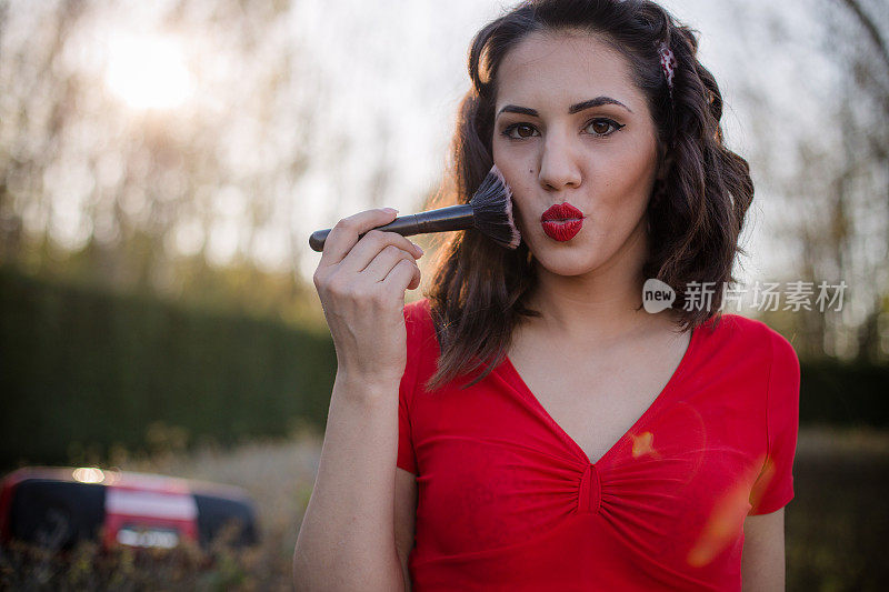 肖像美丽的复古风格的女人使用化妆刷化妆