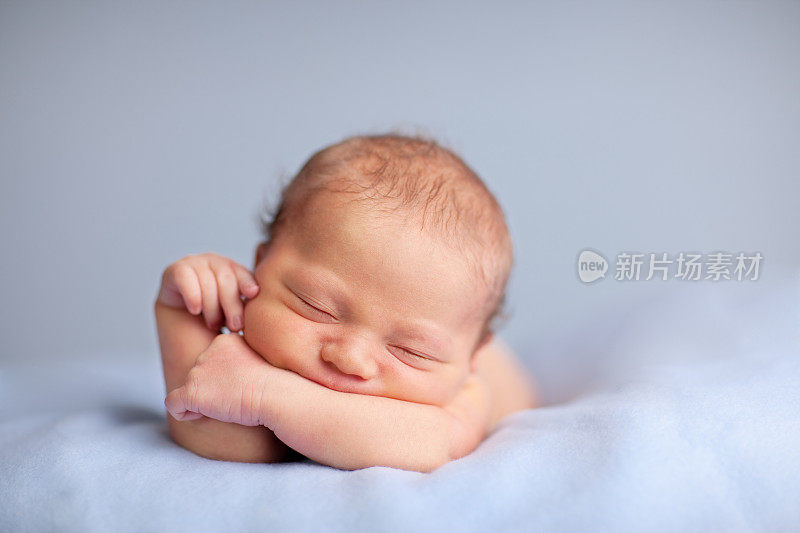 刚出生的男婴安静地睡在蓝毯子上