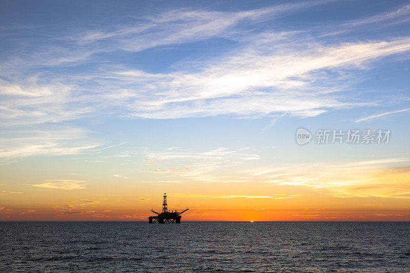 日落时海上石油平台的剪影