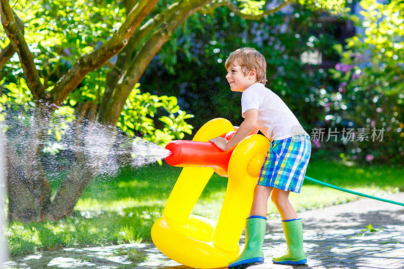 一个小男孩在玩花园里的水管洒水器