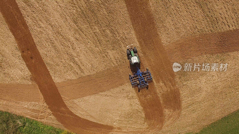 鸟瞰图的拖拉机在一个美丽的农业领域工作在春天的顶部视图
