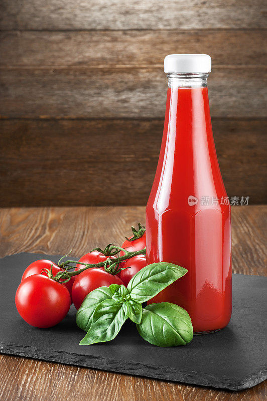 瓶子里有番茄酱、罗勒和西红柿，背景是木制的。