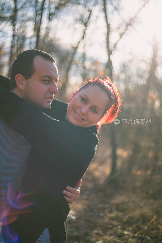 一对美丽的年轻夫妇在秋天的森林里散步