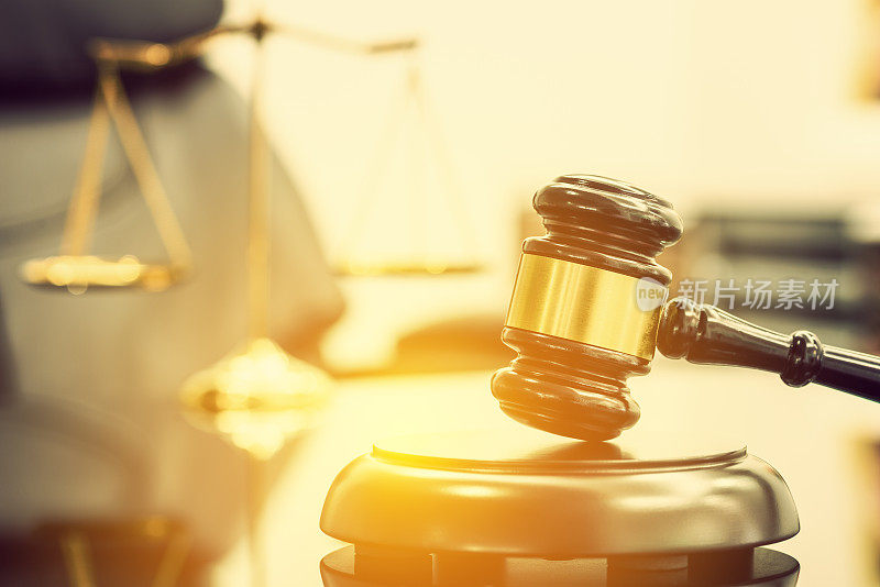 法律事务所的律师，正义和法律概念:木制的法官槌或木锤和音板，法官使用在法庭的桌子上，后面有一个模糊的黄铜正义秤。
