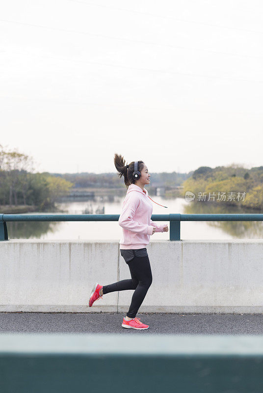 年轻女子在柏油路上伴着音乐奔跑