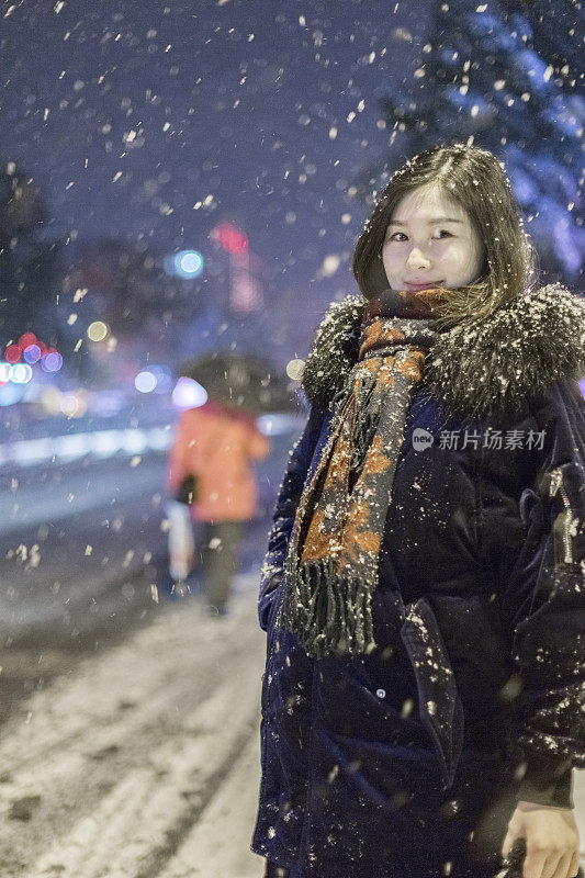美丽的女人站在雪地里的街道上