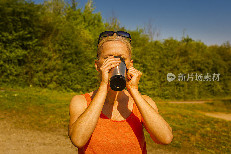 在户外用热水瓶喝水的女人