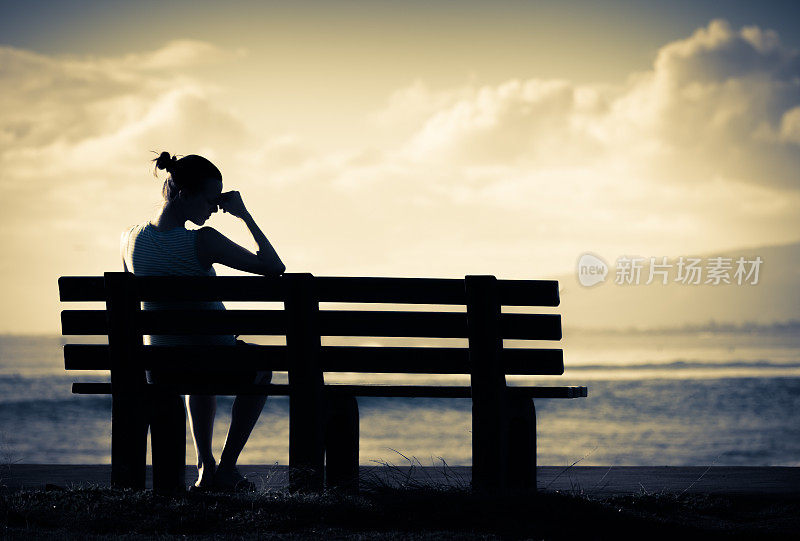 孤独的女人独自坐在长椅上