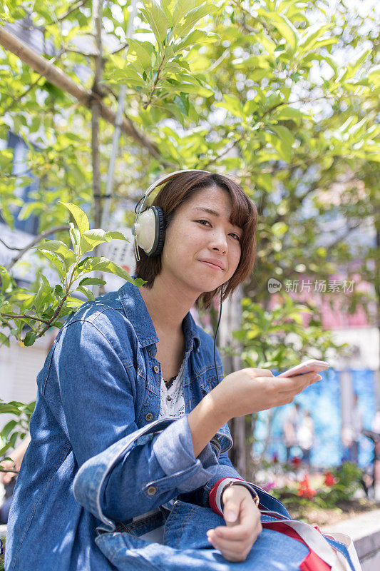 在日本东京原宿街头听音乐的年轻女子