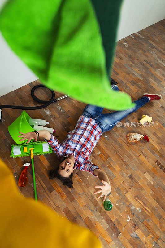 年轻女子躺在地板上，周围都是清洁设备