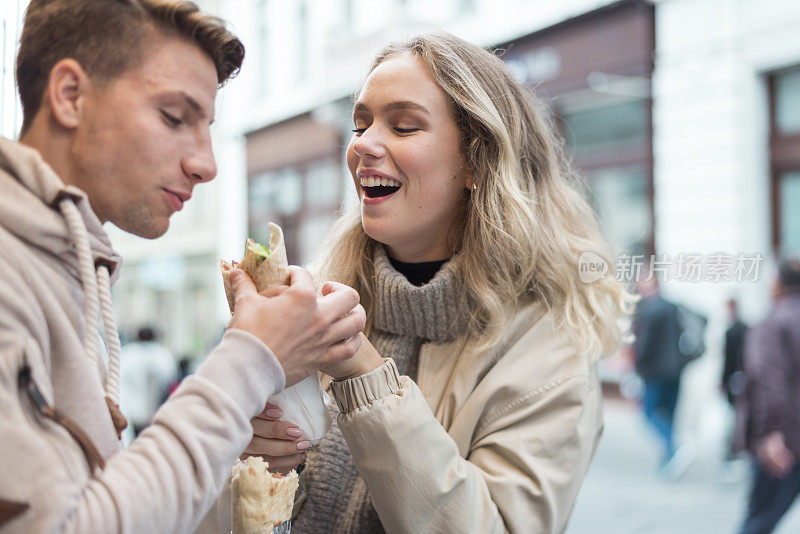 一对年轻夫妇在街上吃着快餐