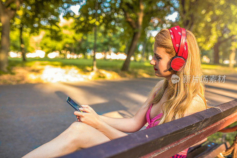 年轻女孩在城市公园里听音乐