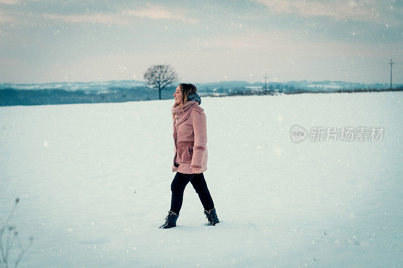 一个年轻女子在一个下雪天走在大自然中