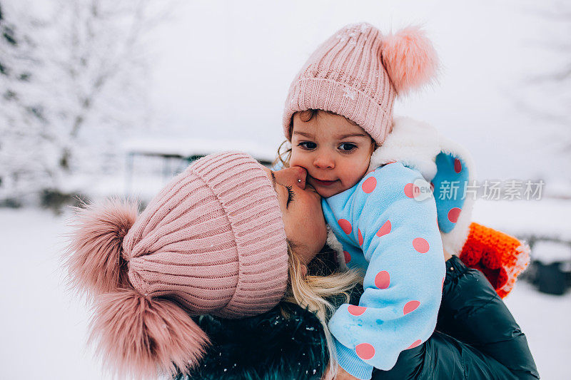 快乐的妈妈喜欢和她的孩子在雪地里玩