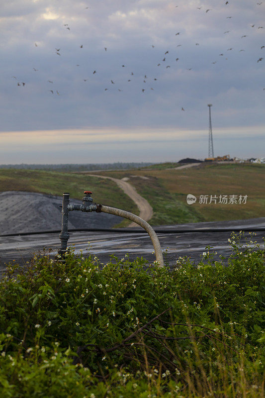 沼气井在回收垃圾填埋场，背景是细胞塔