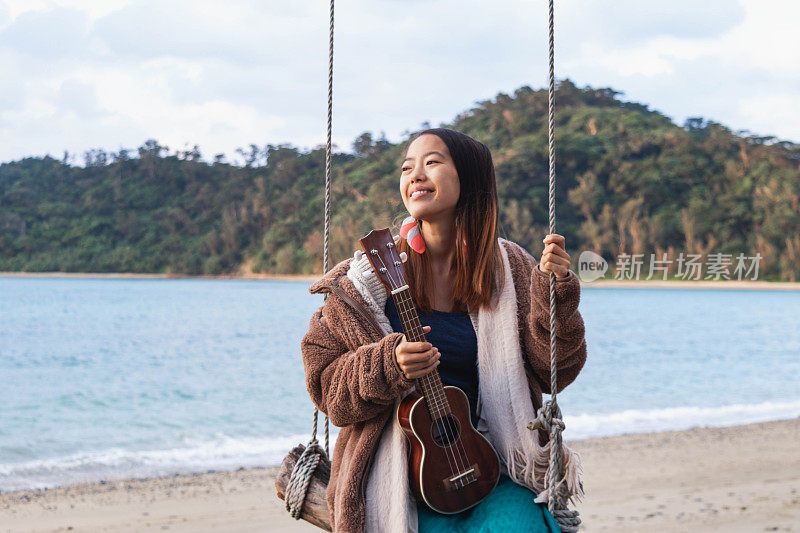 冲绳岛女孩在海滩的原木秋千上