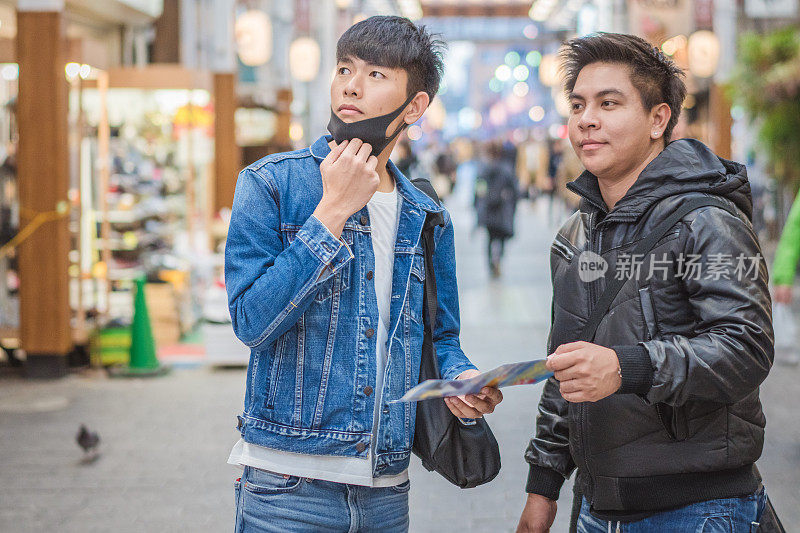 年轻的亚洲男子和日本朋友寻找旅游地点使用手机和花时间在亚洲旅行