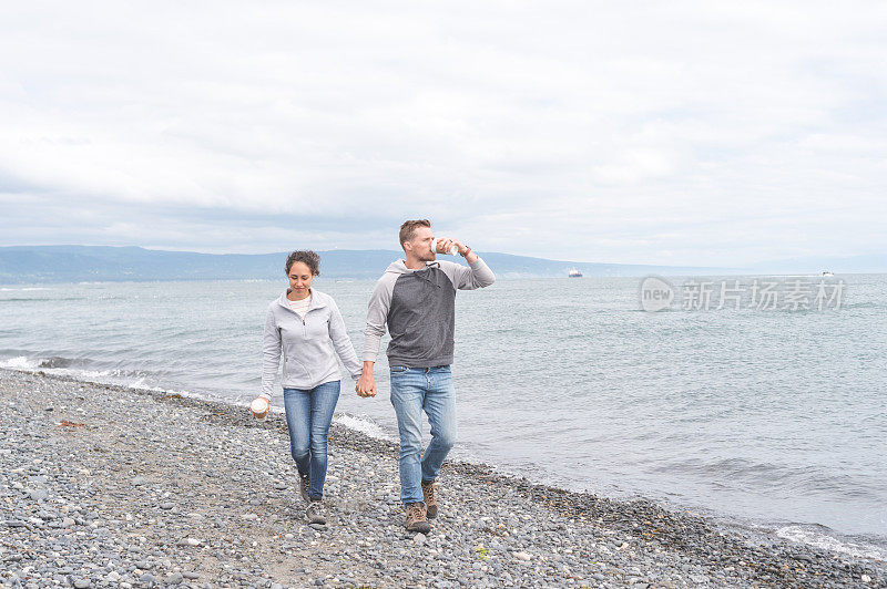 一对年轻的夫妇在一个多岩石的海湾散步