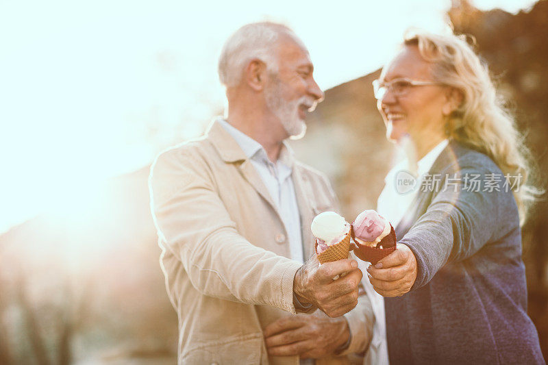 一对老年夫妇在一个阳光明媚的日子里吃着冰淇淋