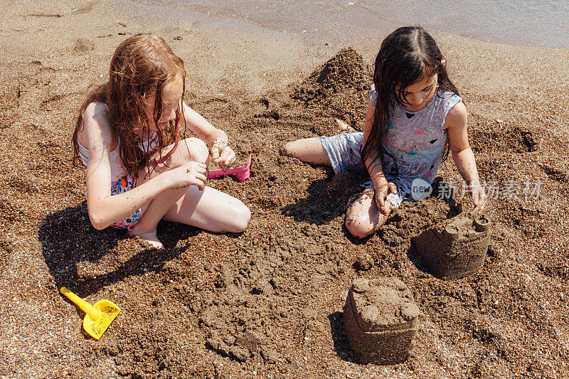 顽皮的女孩在海滩上建造沙堡
