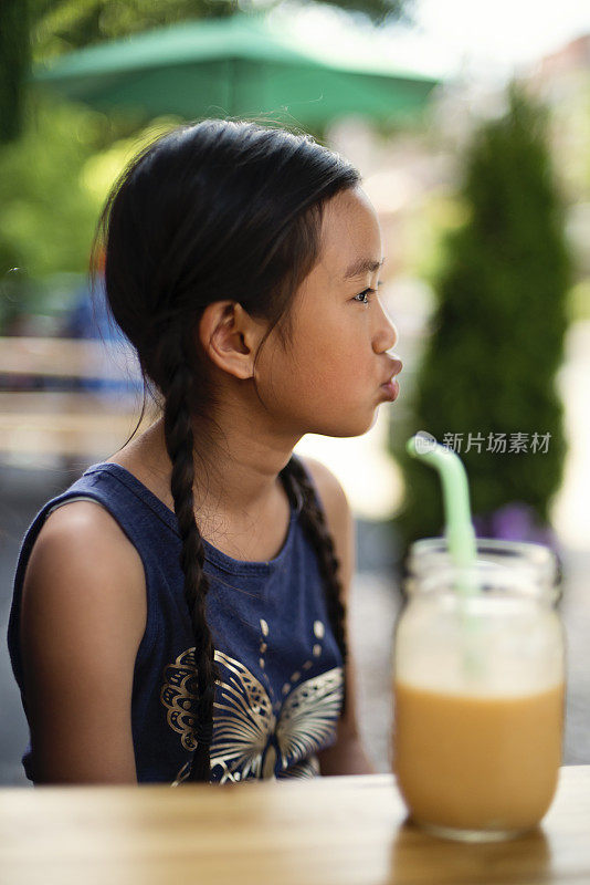 十几岁的女孩用可重复使用的罐子和可重复使用的吸管喝冰沙。