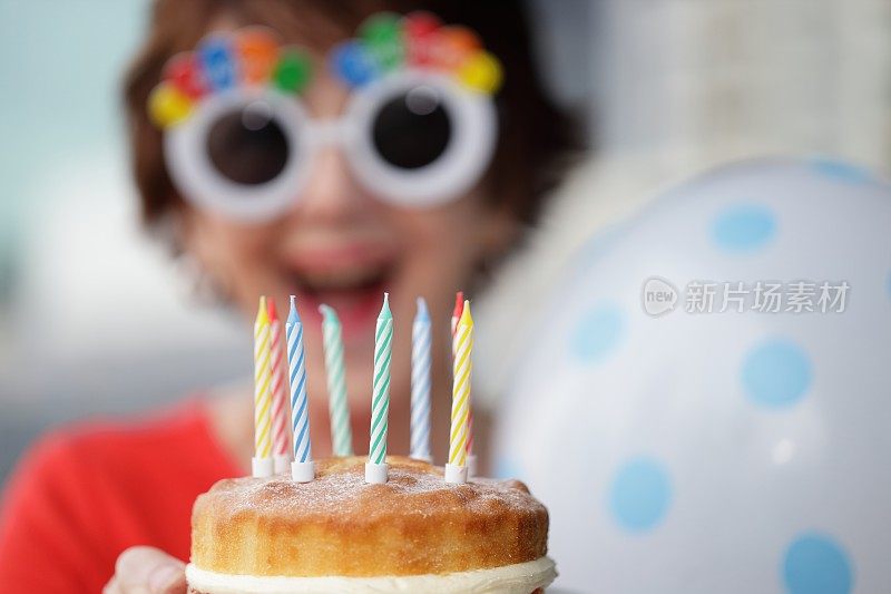 一个面带微笑、戴着新奇太阳镜的女人拿着生日蛋糕。