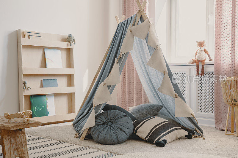 木制家具和带枕头的帐篷在天然斯堪的纳维亚儿童游戏室，真正的照片狐狸