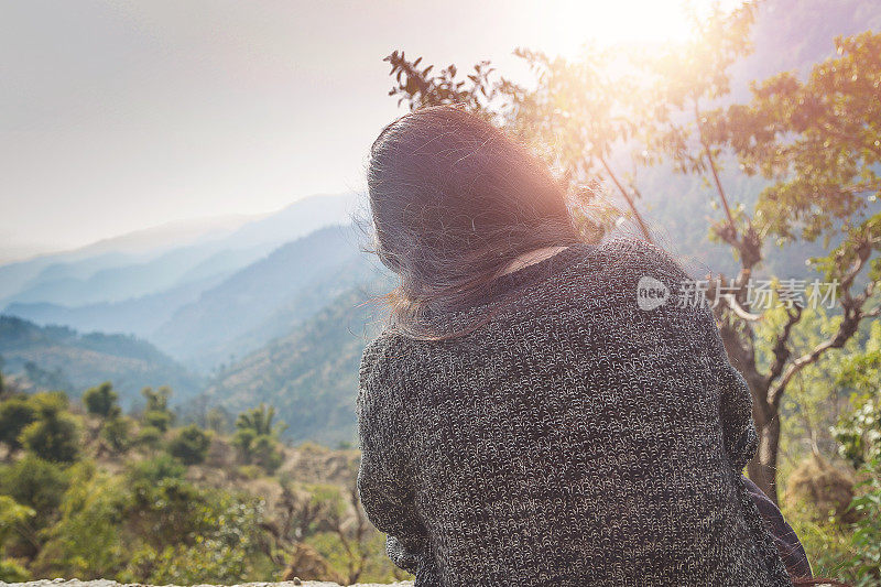 《背谷背山坐在悬崖上的女人，日出》的后视图