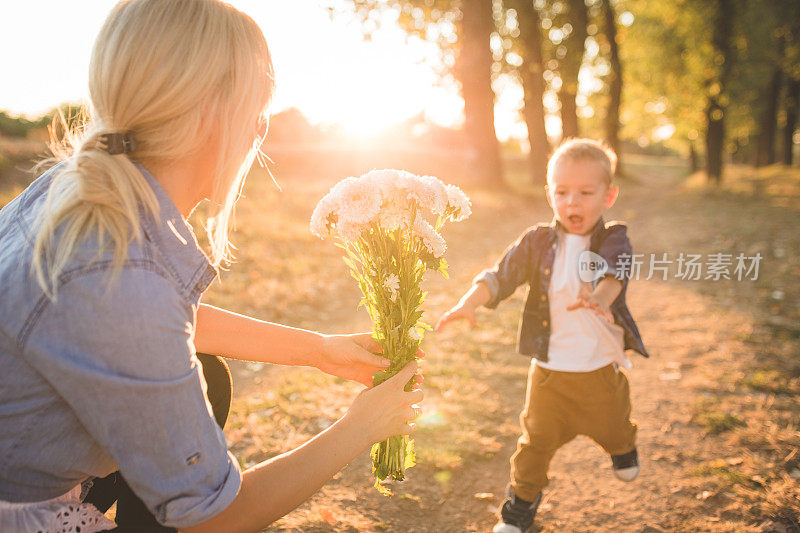 小男孩跑向拿着花的妈妈