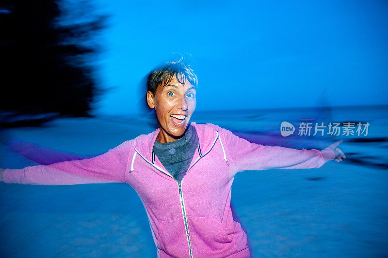 欢快的中年妇女跳舞在晚上的热带海滩假日