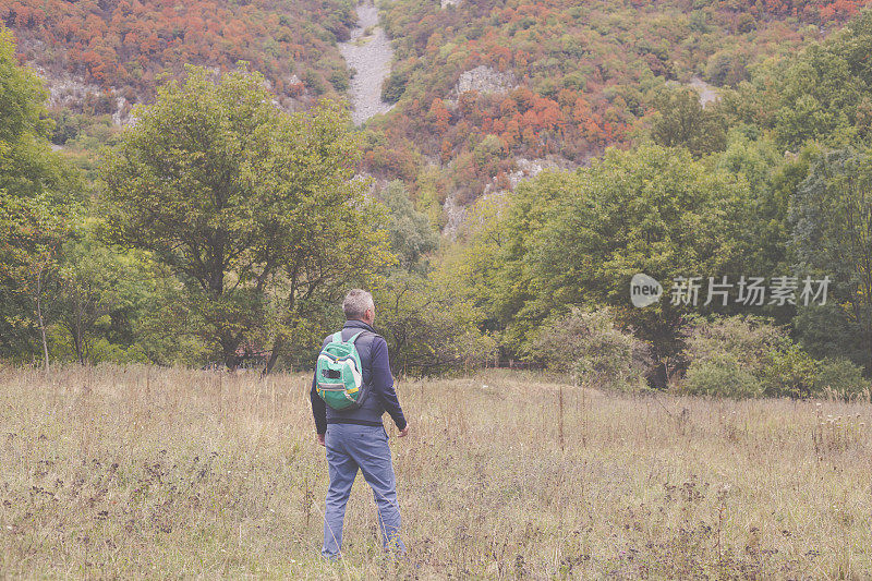 一名成年男子于秋日在美丽的山林中徒步旅行