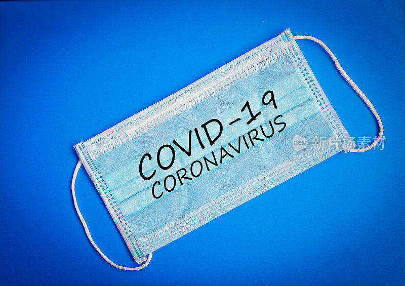 绿色手术防护无菌口罩，以蓝色背景书写COVID-19冠状病毒