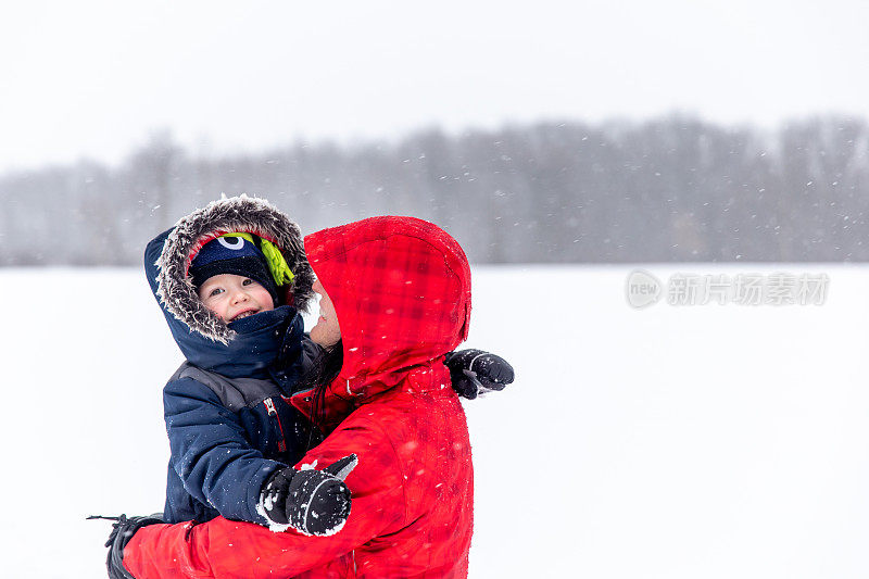 母亲和儿子在暴风雪期间户外玩耍