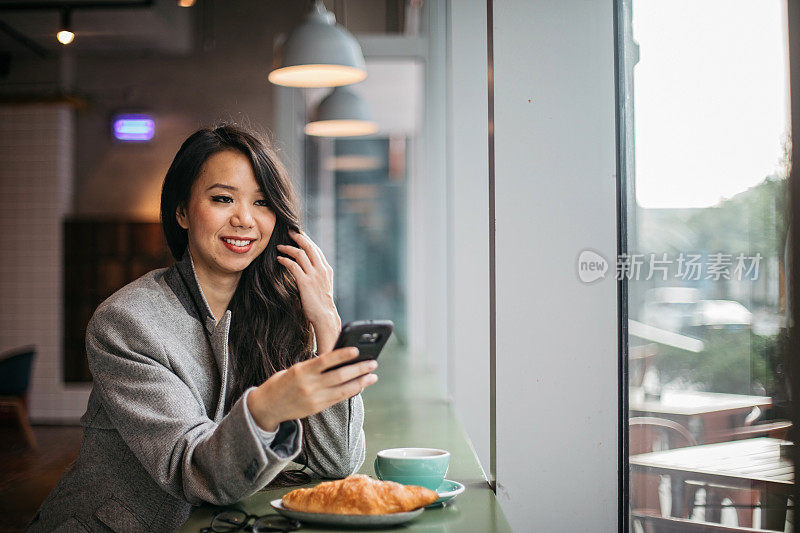 快乐的女人在用电话吃早餐